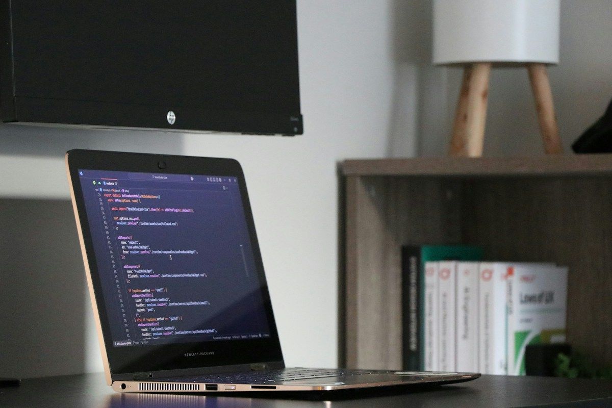 Laptop mit geöffnetem Code-Editor auf einem Schreibtisch